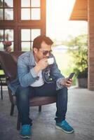 joven con smartphone sonriendo relajándose en el café. foto