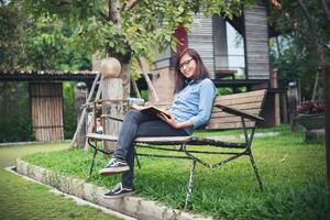 Hipster charming girl relaxing in the park while read book, Enjoy nature around. photo