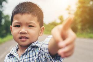 Portrait of cute asian boy pointing his finger to camera. photo