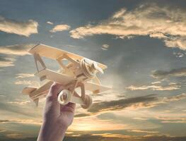 mano sosteniendo un avión de madera en el cielo foto