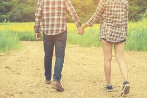 joven pareja hipster dando un paseo por el hermoso campo de flores. foto