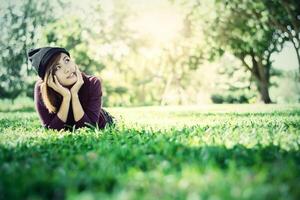 hermosa mujer pensando en algo sobre la hierba verde foto