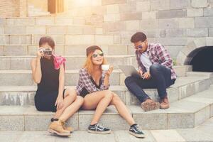 Group of hipster students sitting on a staircase talking and relaxing after school together. photo