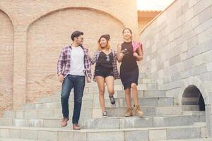 Group of happy hipster teenage students walking down the stairs while talking together. photo