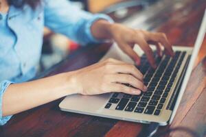 mujer de negocios joven que trabaja en una computadora portátil mientras está sentada en un café bar vintage. foto