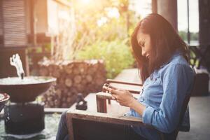 Hipster girl sitting at vintage cafe and using smartphone, Typing on phone. photo