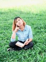 young hipster woman reading a book has an idea pointing with finger up. photo