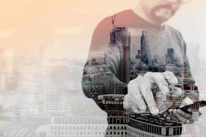 Double exposure of Businessman hand with pen pressing an imaginary button,holding smart phone,blank digital screen graphic virtual,London architecture buildings photo