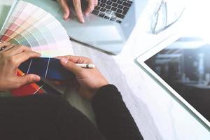 two colleague web designer discussing data and digital tablet and computer laptop with smart phone and design diagram on marble desk as concept photo