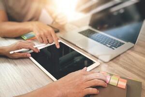 two colleagues interior designer discussing data and blank screen digital tablet and computer laptop with smart phone on wooden desk as concept photo