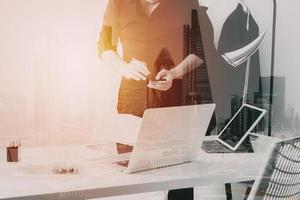 Fashion designer working with mobile phone and using laptop with digital tablet computer in modern studio photo