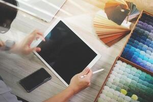 interior designer working with digital tablet and new modern computer laptop with sample material on wooden desk as concept photo