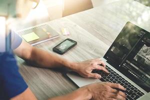 designer hand attending video conference with laptop computer and smart phone at desk in office photo