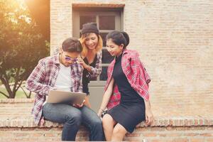 grupo de jóvenes adolescentes hipster que usan laptop al aire libre en vacaciones de verano se divierten y toman tiempo juntos. foto