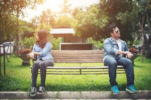 Pareja joven disgustada sentada en un banco en el parque, concepto de estilo de vida de pareja. foto