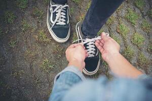 novio hipster atando zapatos a sus chicas mientras se relaja en vacaciones, concepto de pareja enamorada. foto