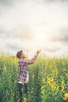 praying man standing in yellow flower field on mountain view background. photo