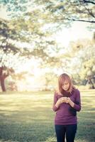 Woman standing in park writing text on smartphone photo