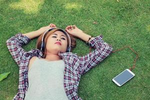 Young hipster woman listening to the music with headphones lying photo
