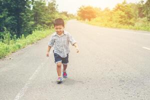 Happy little boy in motion, smiley running on the street. photo