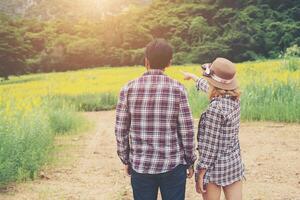 Young hipster couple taking a walk on beautiful flower field. photo