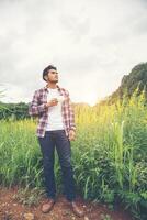 Bearded man with cup of morning coffee walking in the flower field. photo