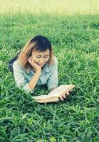 joven y bella mujer hipster leyendo un libro en la hierba. foto