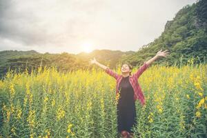 Young beautiful woman standing in the flower field enjoyment. photo