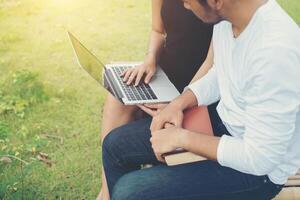 Young education couple sitting on the bench in the outdoors and good weather. And they're happy, Lifestyle concept. photo