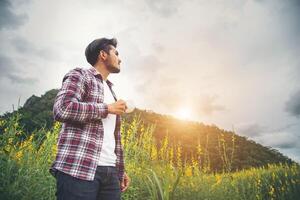 Bearded man with cup of morning coffee walking in the flower field. photo