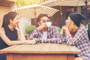 grupo de jóvenes hipster sentados en un café, jóvenes amigos alegres divirtiéndose mientras toman tiempo juntos, disfrutan de la libertad de vacaciones. foto