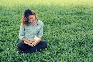 Young woman reading a book in the park on grass. photo