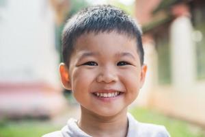 Cierra el retrato de un niño asiático sonriendo en el parque.