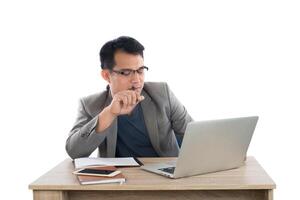 businessman holding a pen thinking sitting at his desk behind his new notebook isolated on white background. photo