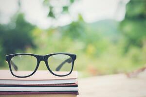 libro y anteojos para leer y escribir sobre fondo exterior de naturaleza borrosa. foto