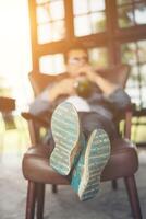 Low angle view of hipster resting with legs on sofa at home. photo