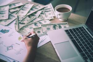 lugar de trabajo del comerciante. la mesa cubierta por billetes de caja, teclado y gráficos financieros. trabajo financiero empresarial. foto