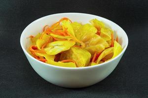 Pickled cabbage with curry and carrots in a plate on a black background photo