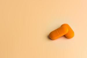 Two large orange pills on a gentle orange background. photo
