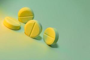 Yellow pills on a light green background. Place for your text. Close-up. Selective focus. photo