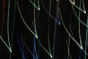 Bright multicolored diagonal V shaped beams of glare on black in cool tones. Abstract background photo