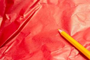 Sharpened yellow pencil on red crumpled paper photo