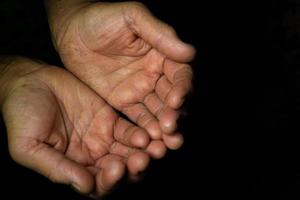 Close up, Two chubby hands with wrinkled palms towards the top of an old woman on a black background with copy space. photo