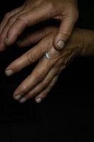 An elderly woman rubs hand cream into wrinkled skin. photo