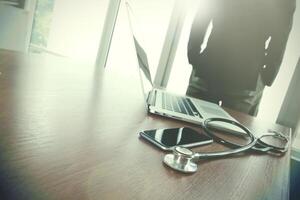 Doctor working at workspace with laptop computer in medical workspace office and medical network media diagram as concept photo