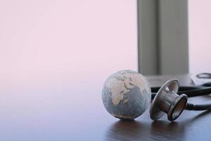 stethoscope and texture globe with digital tablet as medical network concept photo