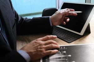 Businessman hand working concept. Documents finance graphic chart. Digital tablet keyboard dock screen computer design smart phone using. Eyeglass on marble desk. Sun flare effect photo