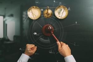 justice and law concept.Top view of Male judge hand in a courtroom with the gavel and brass scale on dark wood table with Vr diagram photo