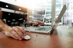 primer plano de la mano del hombre de negocios trabajando en una computadora portátil en un escritorio de madera foto