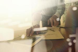 business documents on office table with smart phone and digital tablet and graph business diagram and man working in the background photo